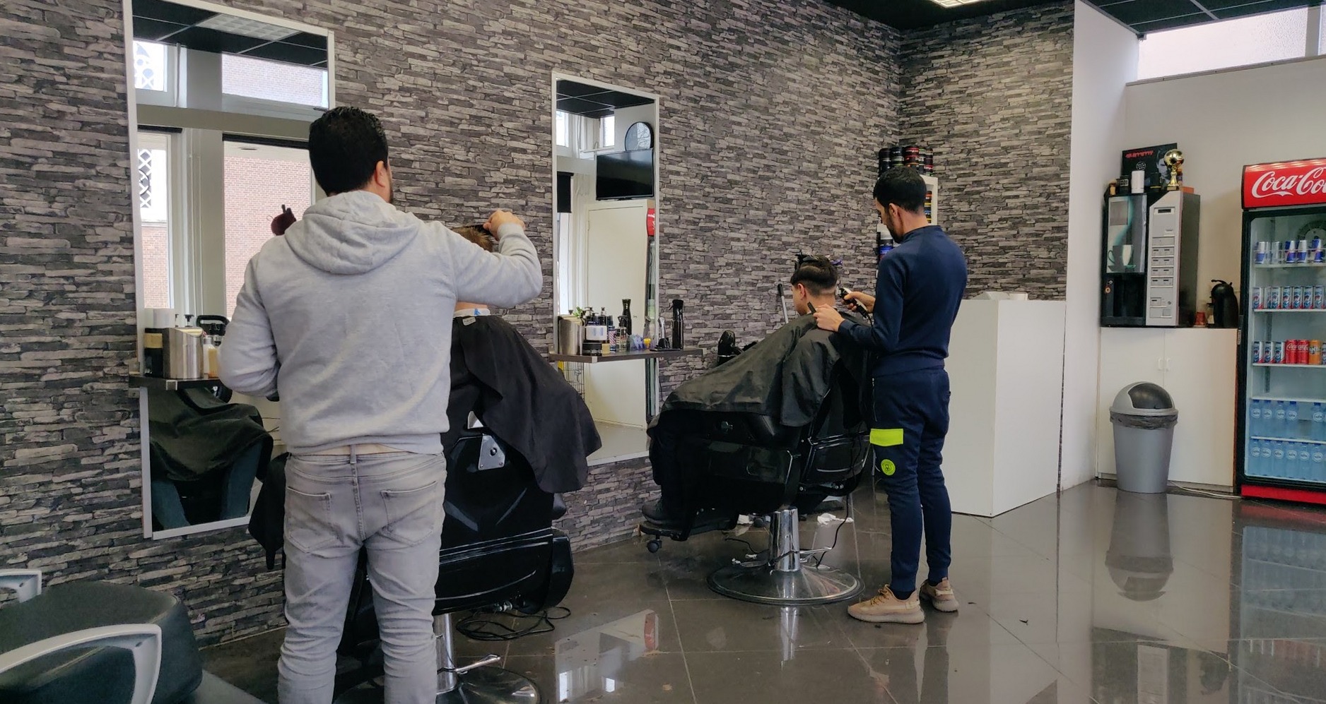 De barbiers aan het werk in de salon van Adam barbershop